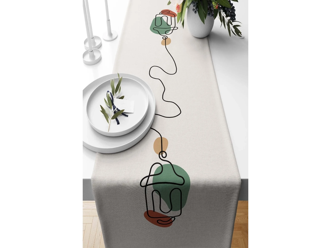 Decorative table runner with abstract plant designs on a white table.